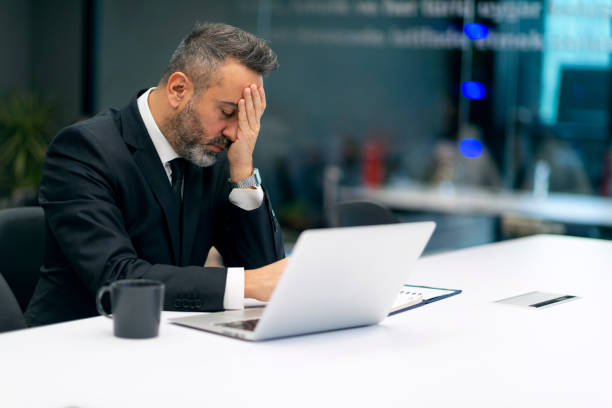 Shocked upset worried businessman reading bad news on laptop in the office.