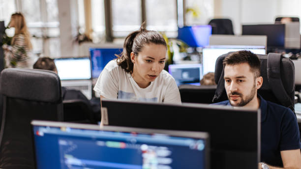Young Caucasian male and female computer programmers working together on a computer at the open space office