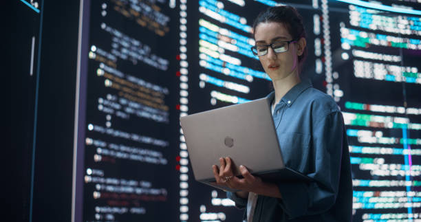 Portrait of Woman Creating a Software and Coding, Surrounded by Big Screens Displaying Lines of Programming Language Code. Female Programmer Working in a Monitoring Control Room. Futuristic Concept